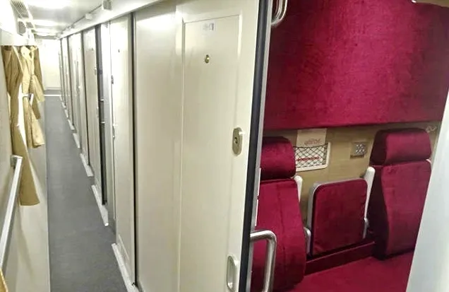 The bright and clean interior of a Special Express No. 23 train carriage with red sleeper seats.