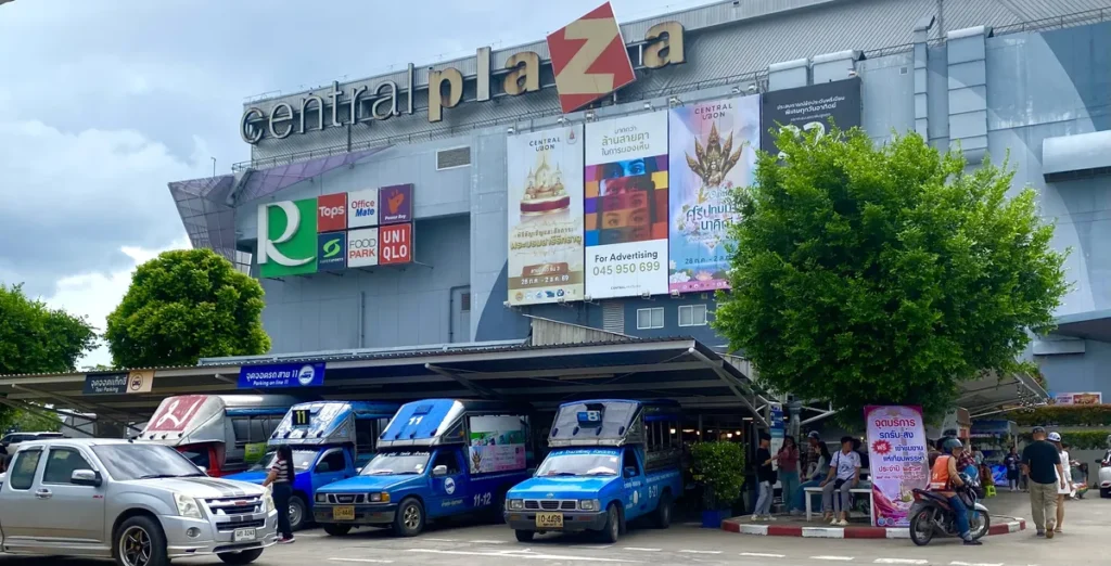 Several blue Songthaew shuttle buses parked at the Line 11 terminal outside the Central Plaza shopping mall in Ubon Ratchathani.