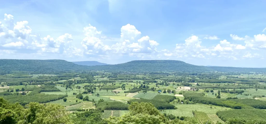 A wide panoramic view of the green countryside plains and rolling hills in Northeast Thailand.
