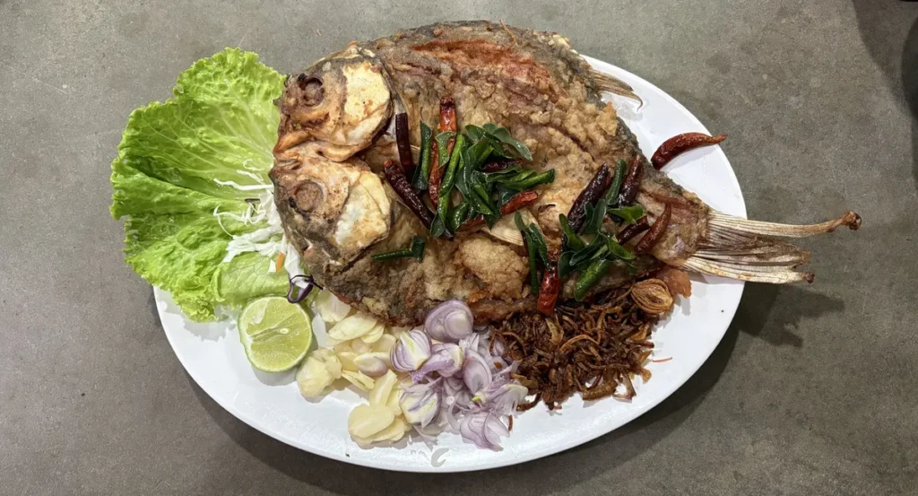 A traditional serving of Pla Som pan-fried fermented fish with raw shallots, garlic and herbs in Isaan.