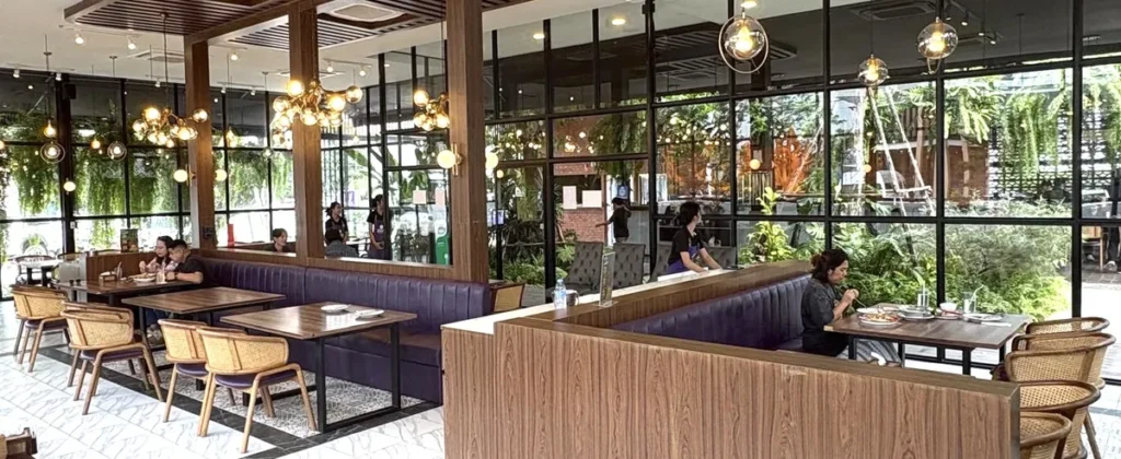 The modern air-conditioned interior of Tum Kratoei restaurant in Ubon Ratchathani, a premium location for authentic Isaan cuisine featuring stylish wooden decor and garden views.