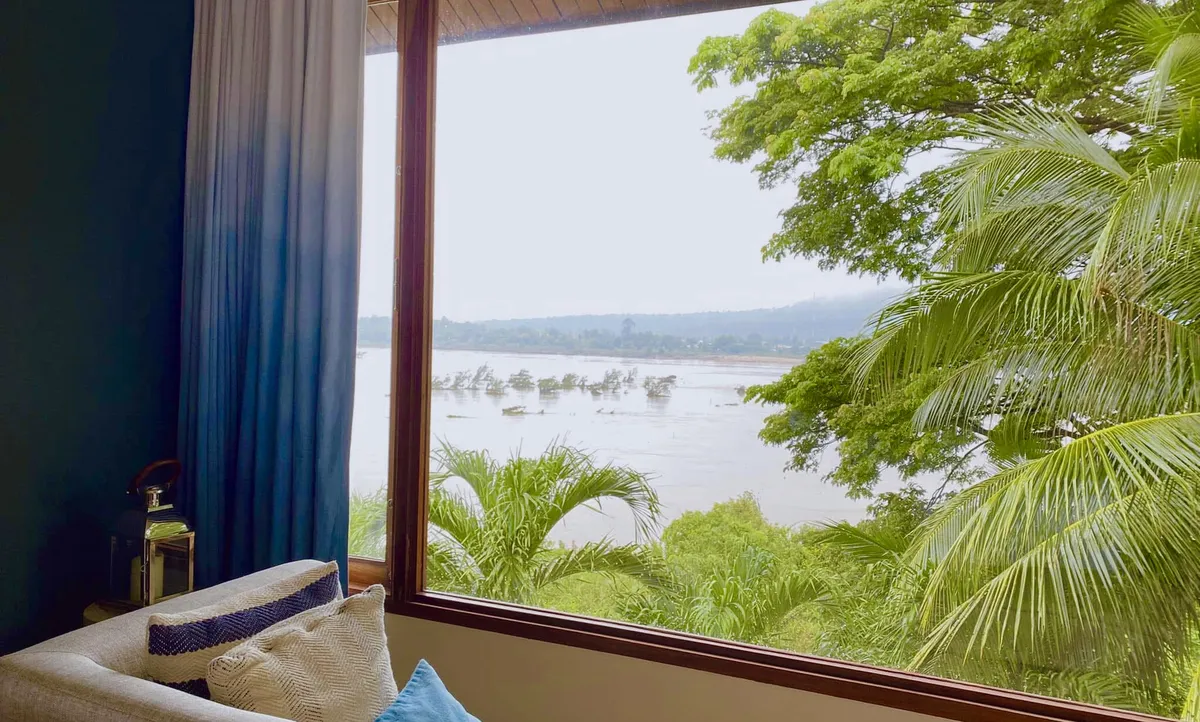 A comfortable hotel room view through a large window overlooking the Mekong River in Ubon Ratchathani.